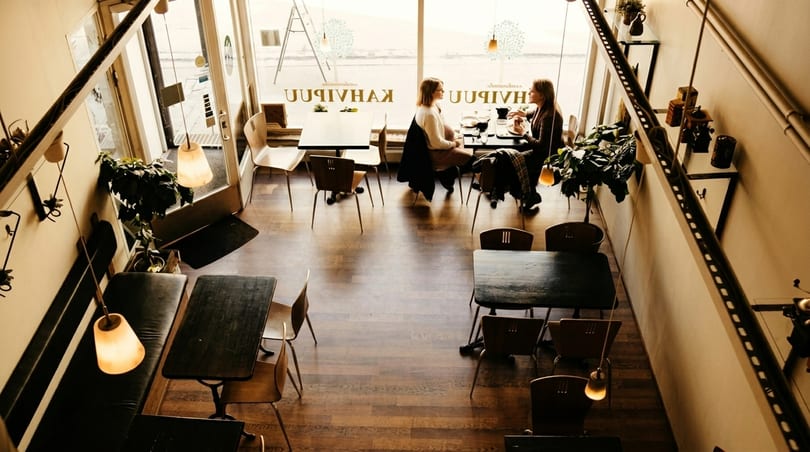 Overhead view of a cozy cafe with two women dining by a large window.