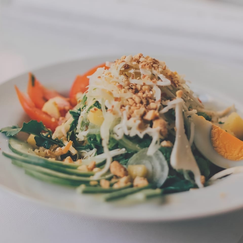 Fresh salad with greens, shredded vegetables, peanuts, avocado, tomato, and hard-boiled egg.